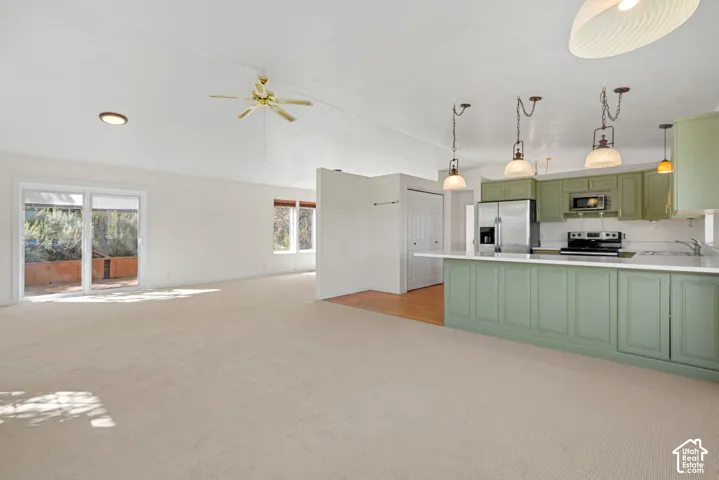 Open-concept living space with sliding glass doors, ceiling fan, and carpet flooring