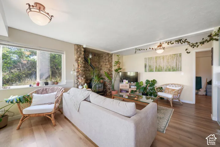 Light wood-finish flooring, stone-clad fireplace, white window trim, and semi-flush mount lighting fixtures