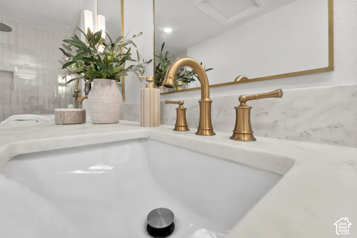 Built-in sink with brass-finish faucet, white countertop, and framed wall mirror