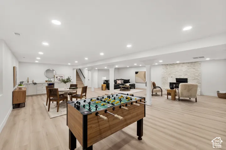 Spacious recreational area featuring wood-finish flooring, recessed lighting, and a stone-clad fireplace