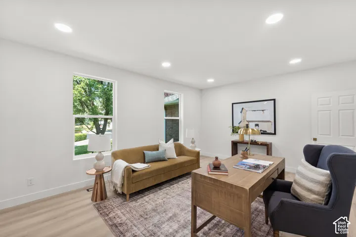 Recessed lighting, wood-finish flooring, two windows, paneled door, and a wooden desk