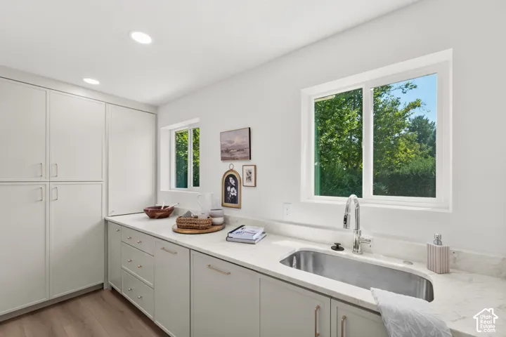 Integrated cabinetry with ample storage, stainless steel undermount sink, dual windows, recessed ceiling lighting, and wood-finish flooring