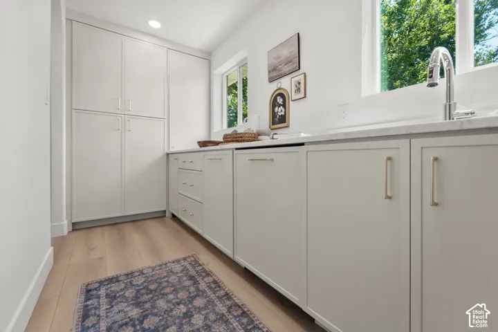 Wood-finish flooring, recessed lighting, built-in cabinetry, polished chrome faucet, and a large window