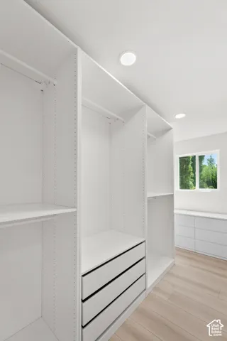 Integrated custom closet system with white shelving, built-in drawers, and recessed lighting