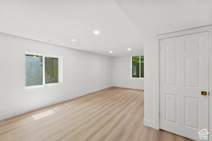 Expansive room featuring light wood-finish flooring, recessed lighting, and multiple windows