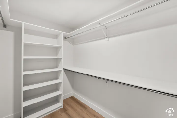 Built-in shelving unit, multiple hanging rods, white walls, and wood-finish flooring