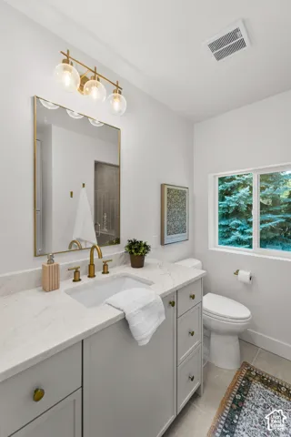 Vanity with undermount sink, brass hardware, and a stone countertop