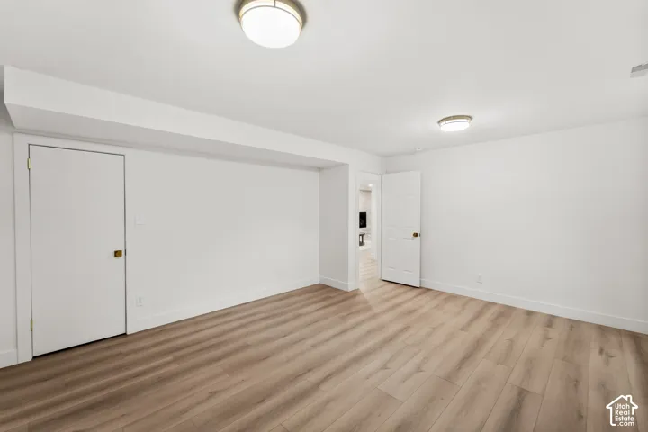 Wood-finish flooring throughout the room, featuring white walls, white doors, and flush-mount ceiling lighting