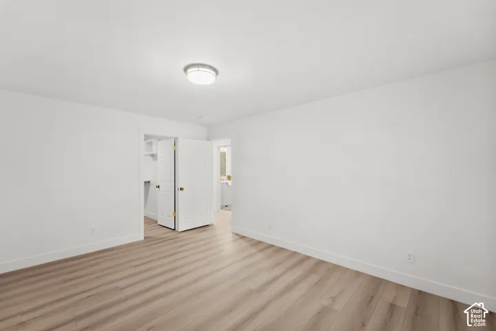Neutral white wall finishes, light wood-finish flooring, and a flush-mount ceiling light fixture