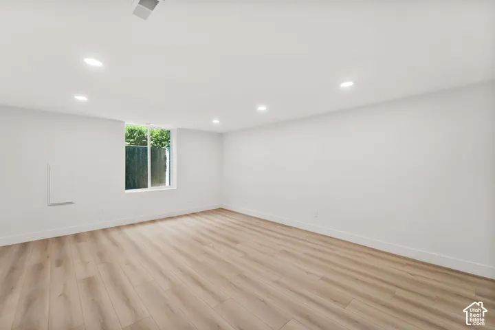 Recessed lighting, wood-finish flooring, white walls, and a window