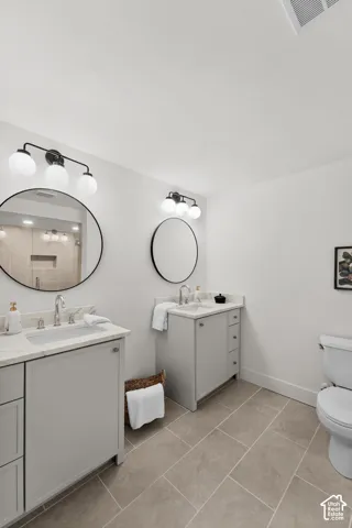 Dual vanity with undermount sinks, stone countertops, and contemporary light fixtures