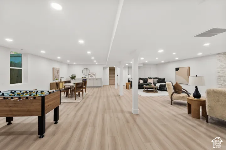 Spacious room featuring light wood-finish flooring, recessed lighting, and white walls