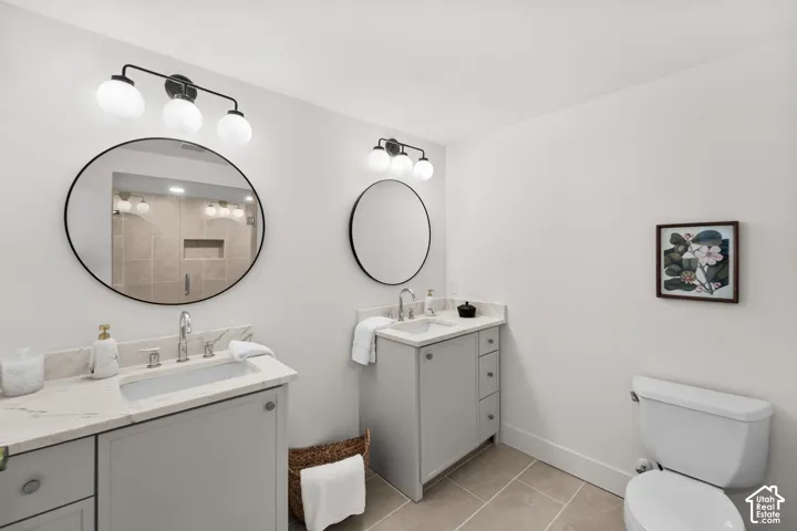 Dual sink vanity with light gray cabinetry, white countertops, and circular framed mirrors