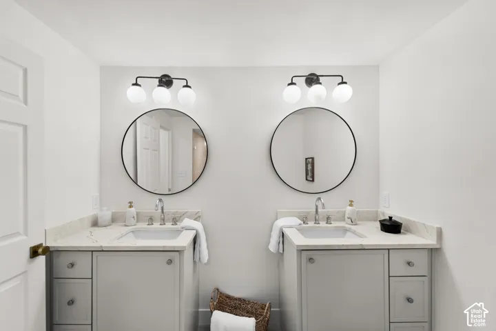 Dual vanities with undermount sinks, stone countertops, and dark-framed circular mirrors