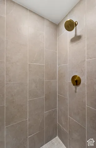 Shower with full-height large format tiling, a bronze finish shower head, and a bronze finish single-handle control