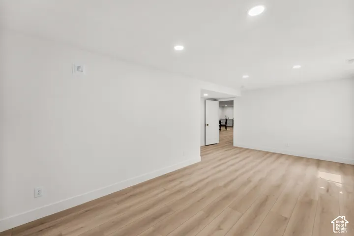 Recessed lighting, wood-finish flooring, white walls, and a white interior door