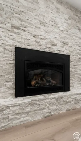 Modern fireplace surround featuring a linear gas insert with a sleek black frame, complemented by stacked stone cladding in neutral tones