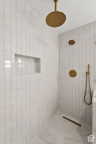 Tiled shower enclosure featuring a ceiling-mounted rainfall showerhead, wall-mounted showerhead, and handheld spray