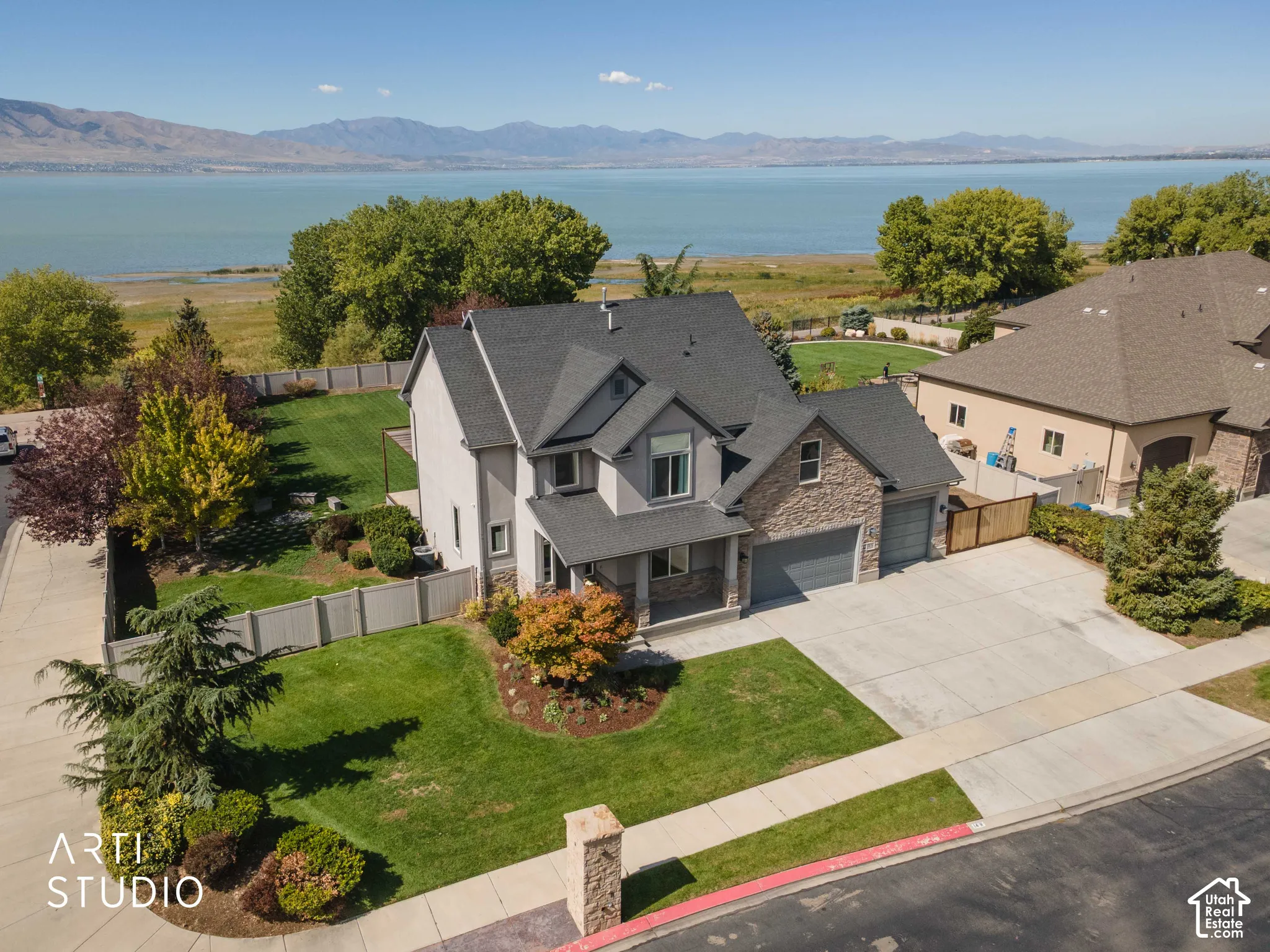 Two-story residence with a stone and siding exterior, multi-car driveway, and an attached two-car garage