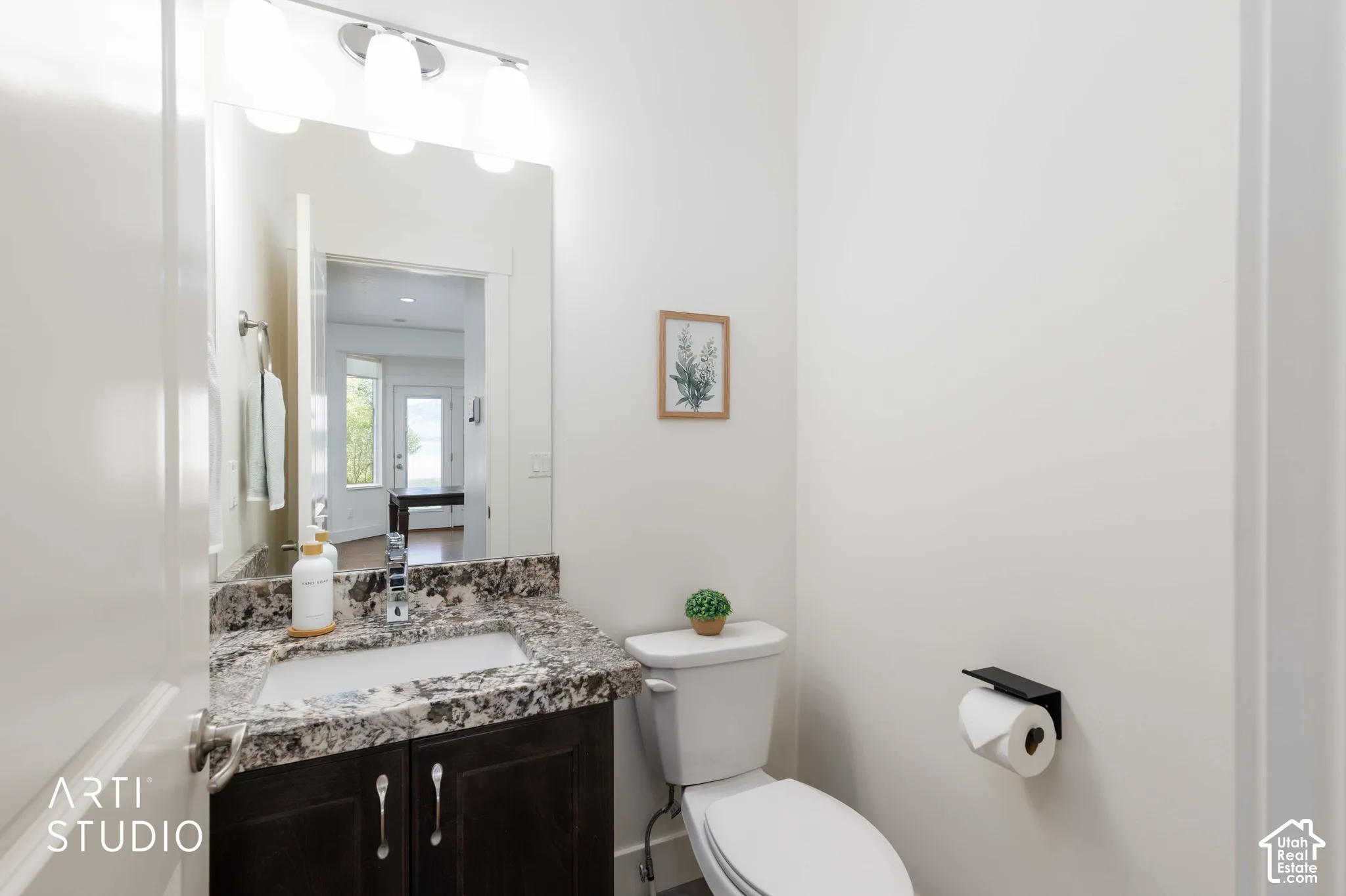 Vanity with a granite countertop, undermount sink, and dark wood-finish cabinetry