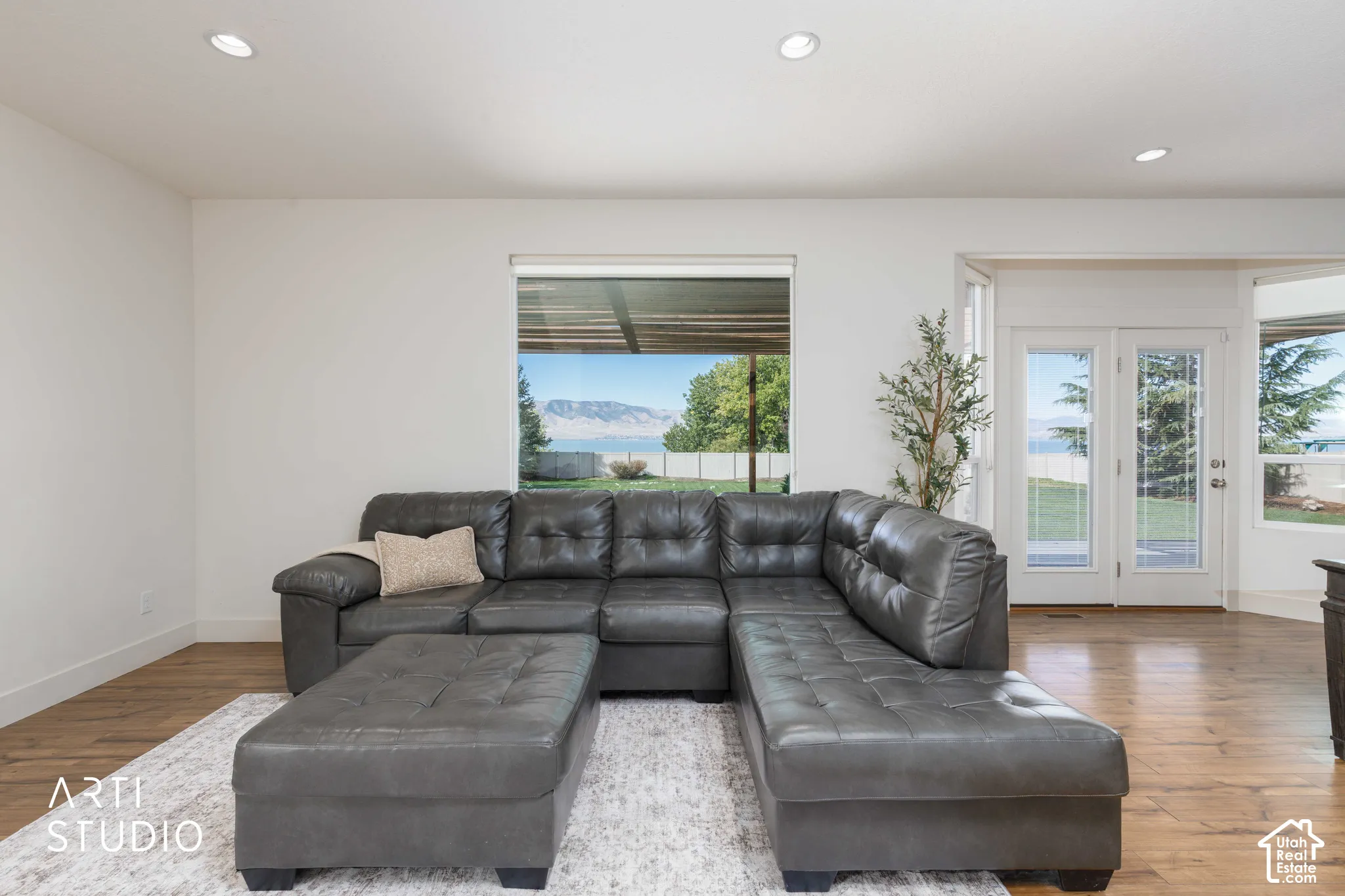 Recessed lighting, white walls, wood-finish flooring, large window, and double glass-paneled doors