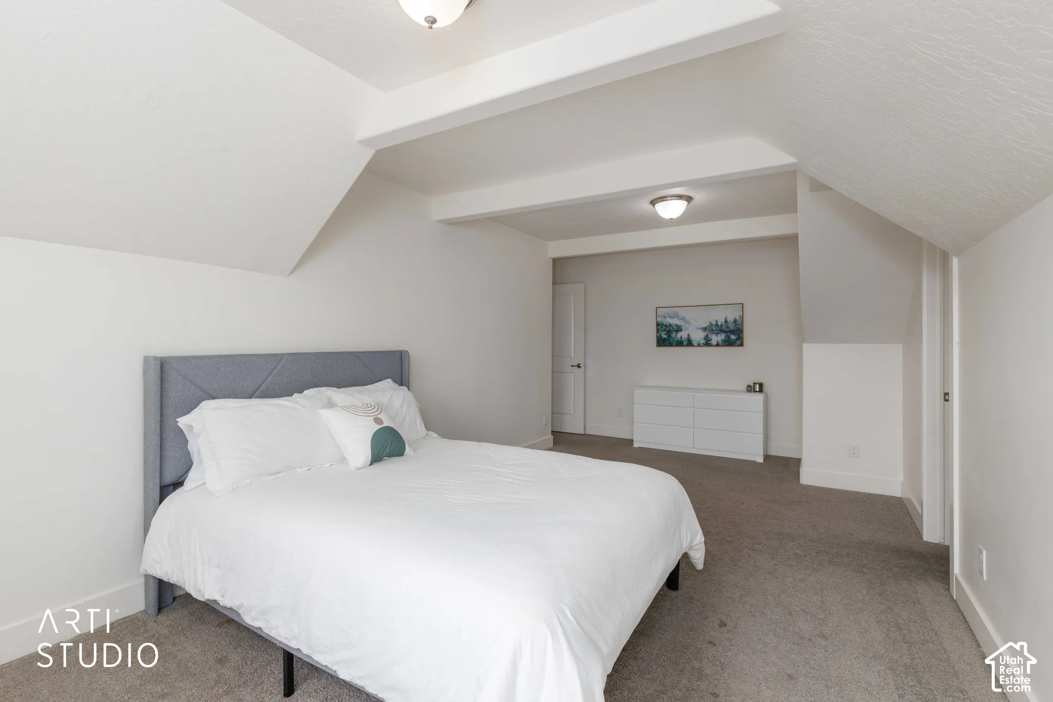 Carpeted flooring with sloped ceilings, white painted walls, and overhead lighting