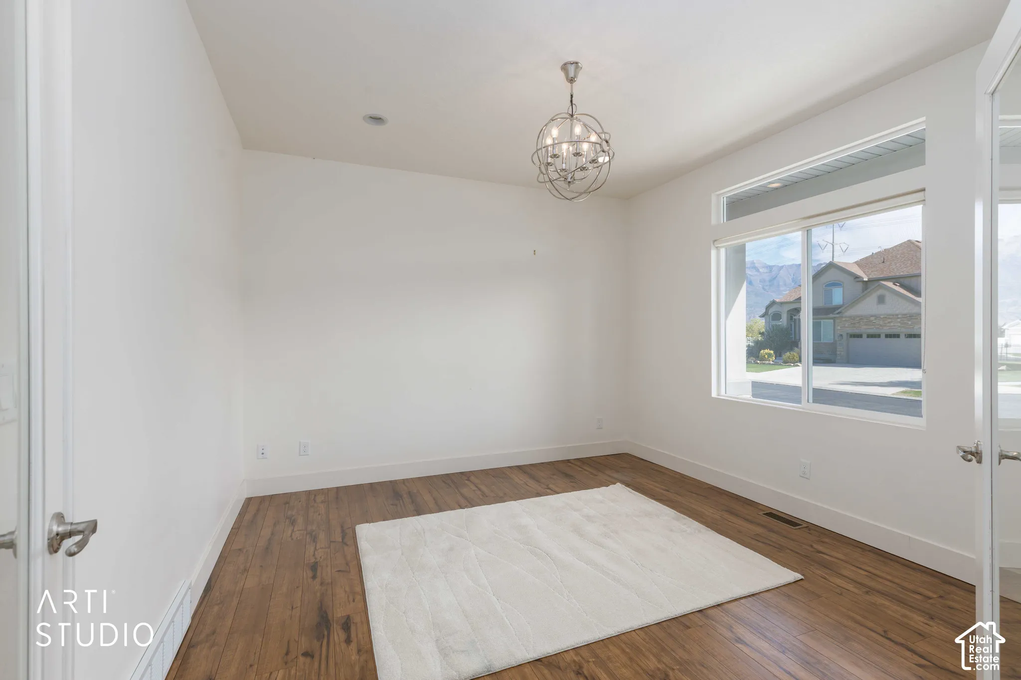 Bright room featuring wood-finish flooring, a contemporary chandelier, and large windows
