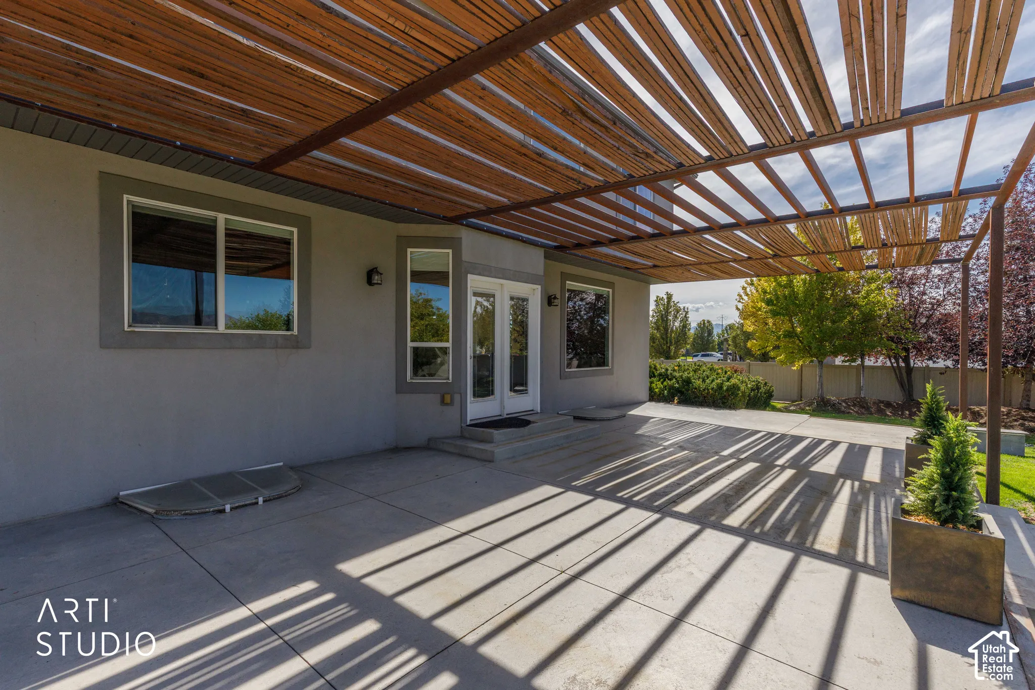 Expansive concrete patio featuring a wood slat pergola