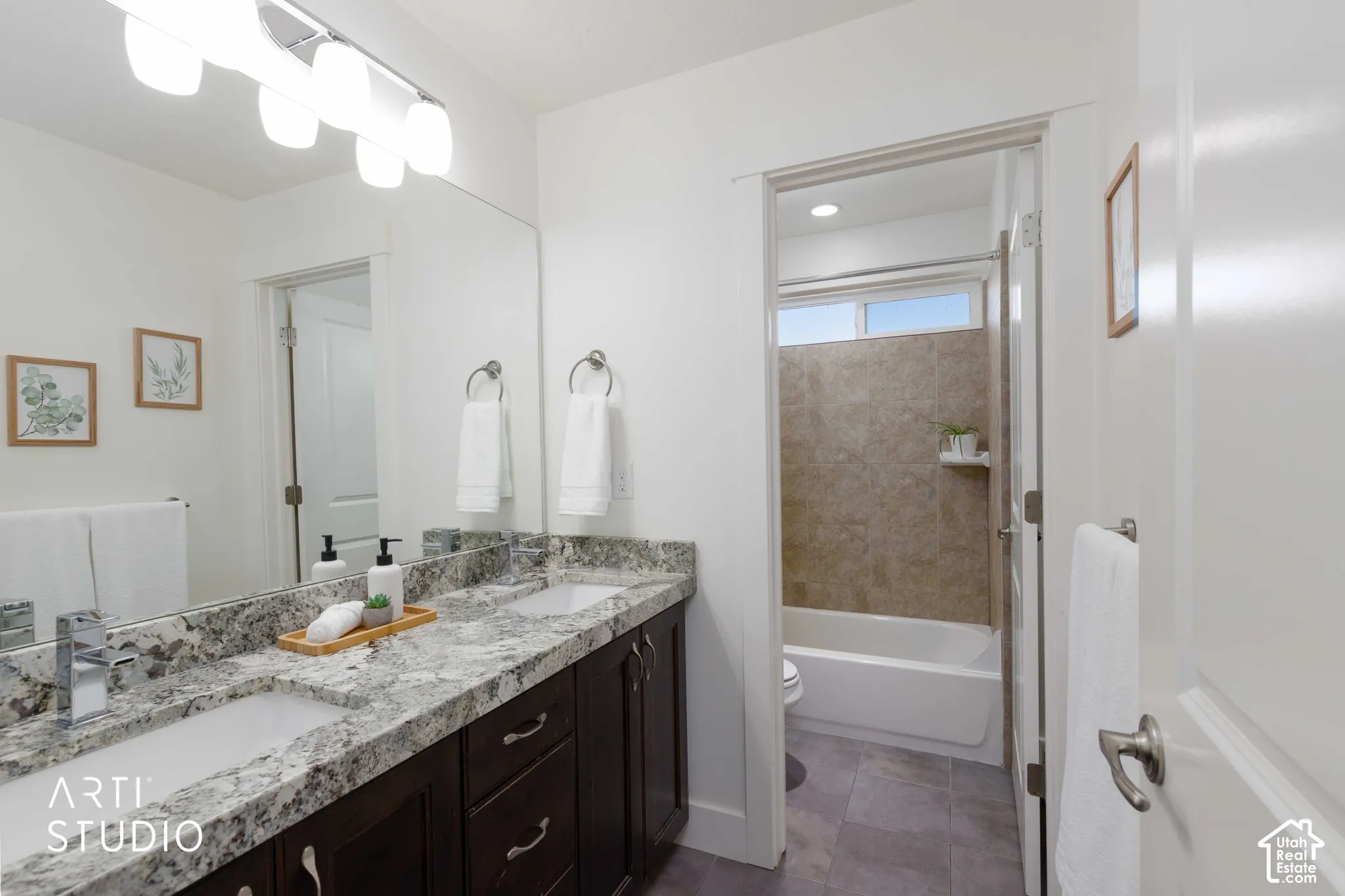 Dual vanity with stone countertop, dark wood-finish cabinetry, and contemporary light fixtures
