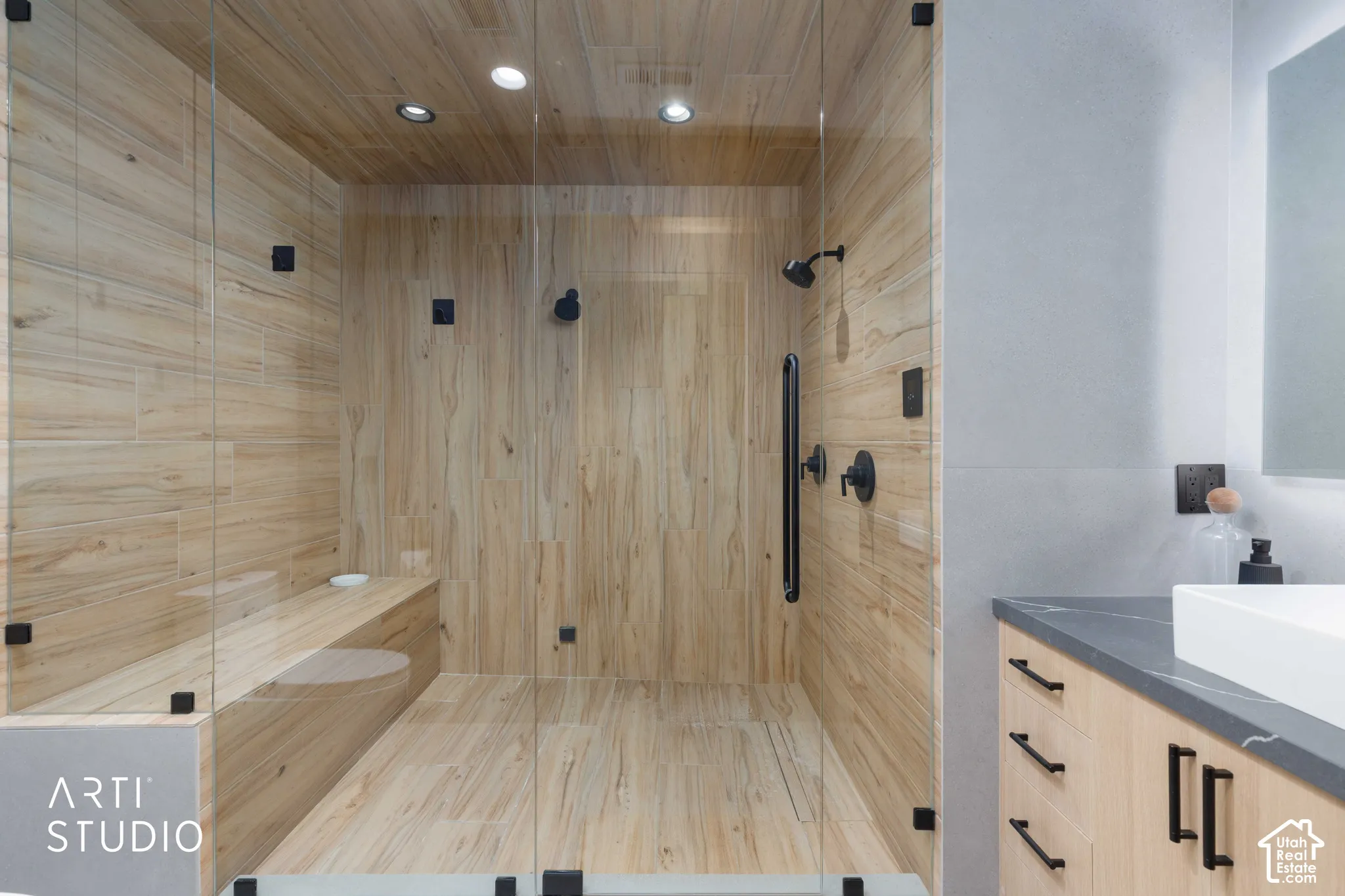 Glass-enclosed shower with wood-finish tile walls and a built-in bench