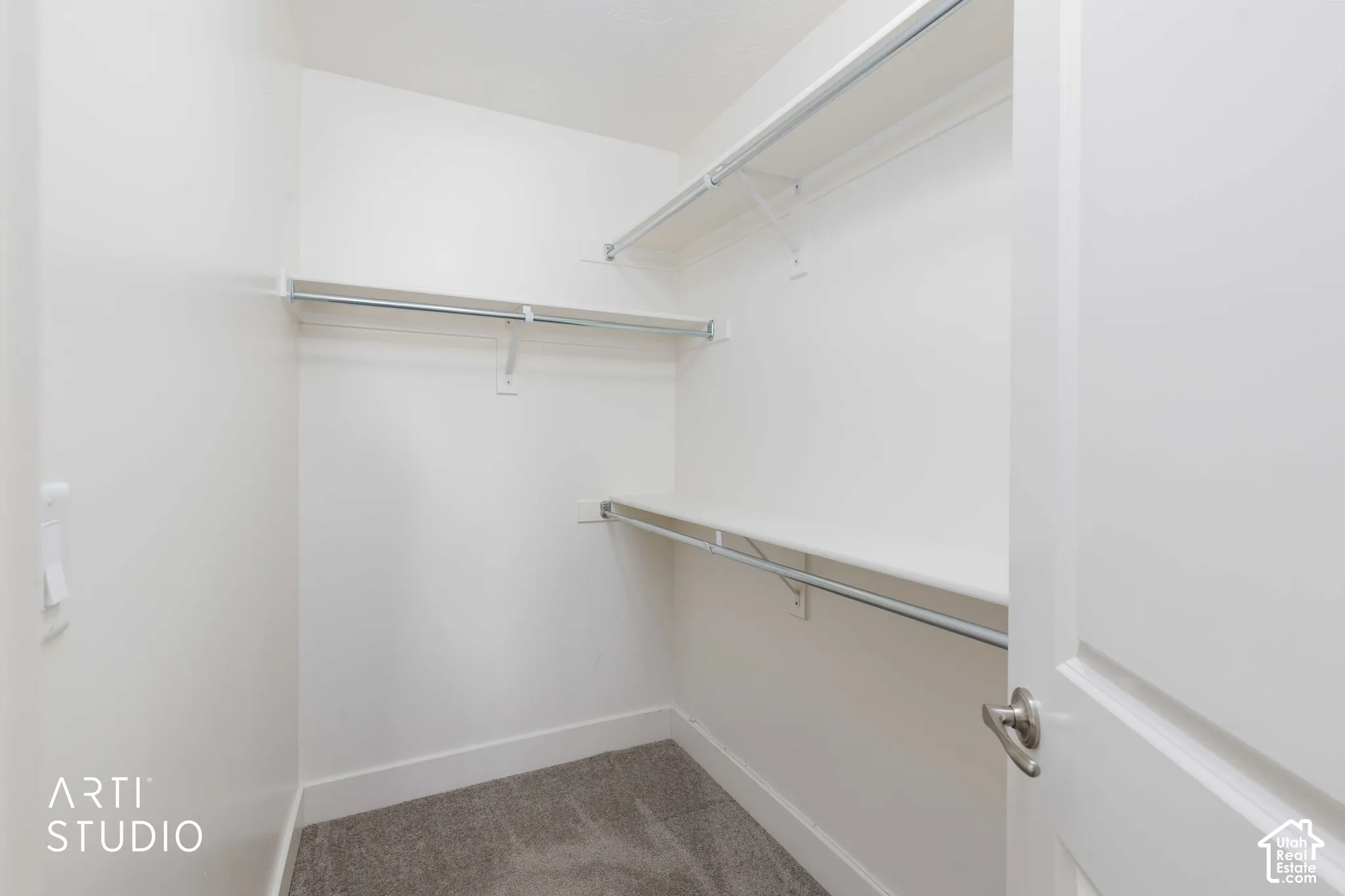 Walk-in closet with white walls, gray carpet, and multiple shelving units