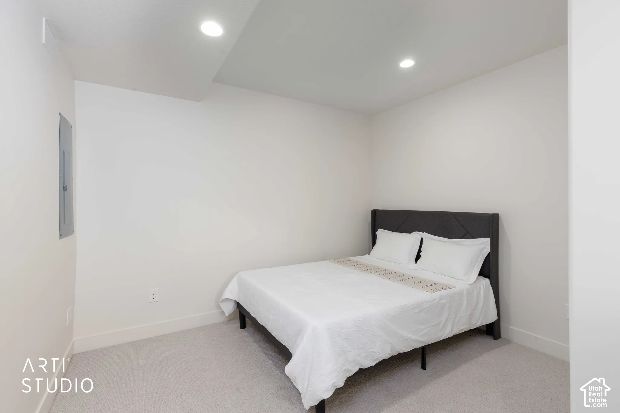 Recessed lighting illuminates the carpeted flooring and crisp white walls