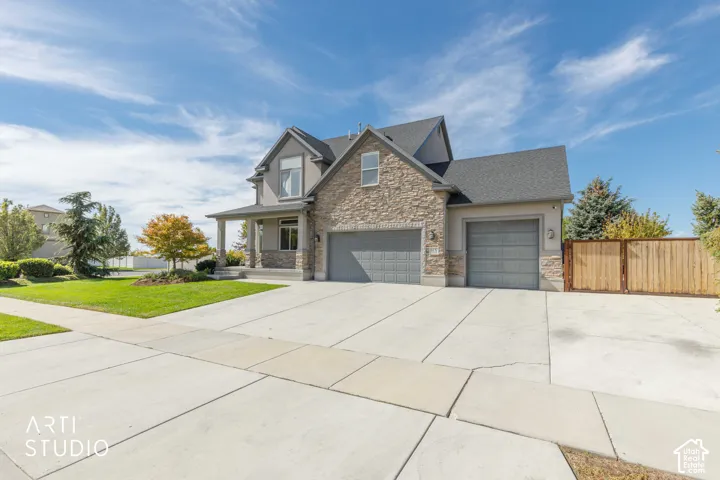 Stone and siding exterior with a covered front porch, dual garage doors, and a concrete driveway