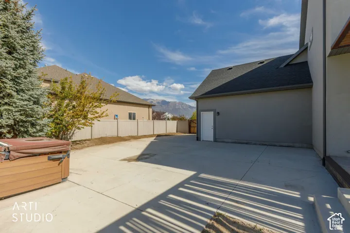 Expansive concrete patio with a stucco exterior and pitched shingle roofline
