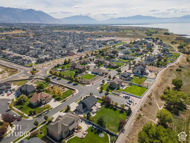 Aerial perspective of a residential community featuring single-family homes, mountain scenery, and a prominent body of water