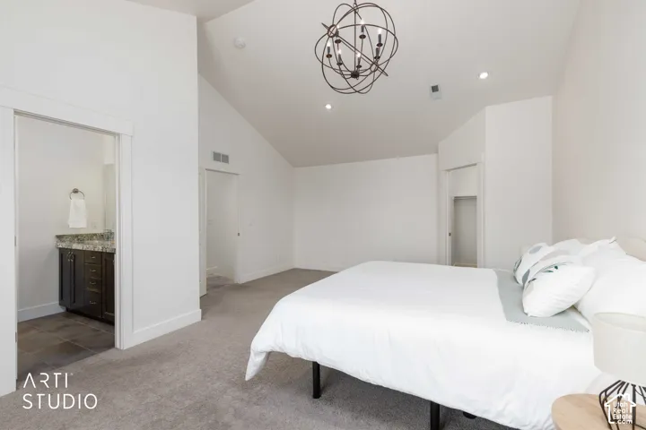 Vaulted ceiling with an orb chandelier, recessed lighting, carpeted flooring, and a bathroom vanity with a countertop and undermount sink