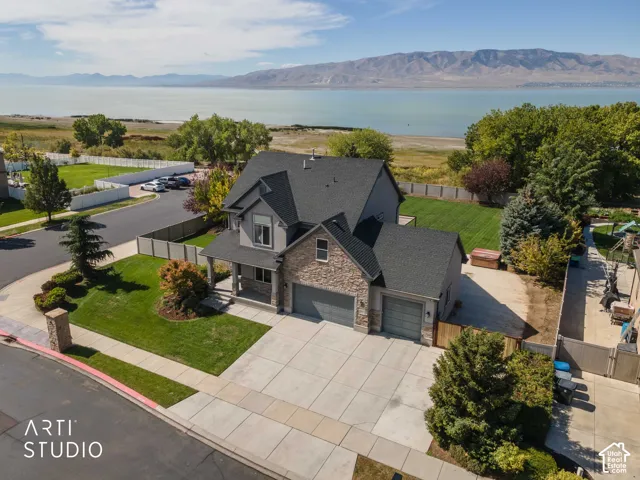 Two-story residence with a stone and siding exterior, multi-car garage, covered porch, and a landscaped front yard