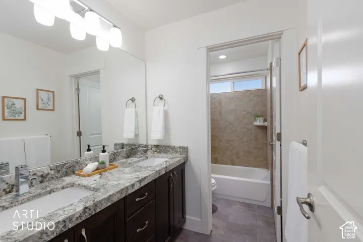 Dual vanity with stone countertop, dark wood-finish cabinetry, and contemporary light fixtures