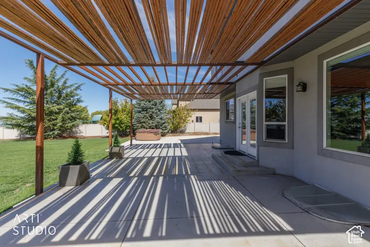 Spacious concrete patio with a slatted pergola overhead