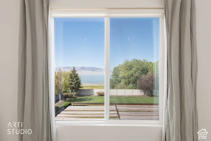 Large window with natural light, showcasing a landscaped backyard, distant lake, and mountainous backdrop