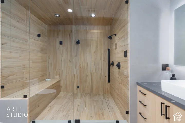Glass-enclosed shower with wood-finish tile walls and a built-in bench