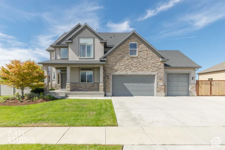Two-story stucco and stone exterior, covered front porch, two-car garage, single-car garage, and concrete driveway