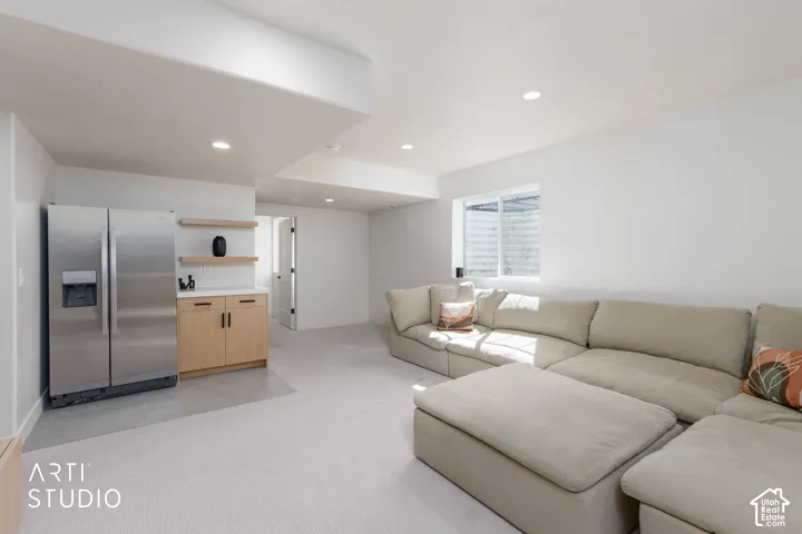 Recessed lighting, light wood-finish cabinetry, stainless steel refrigerator, white countertop, and window