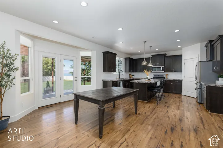 Spacious kitchen with wood-finish flooring, dark wood cabinetry, and a central island with bar seating