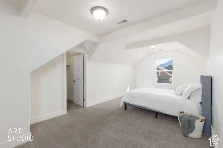 Vaulted ceilings with exposed beams, recessed lighting, and carpeted flooring