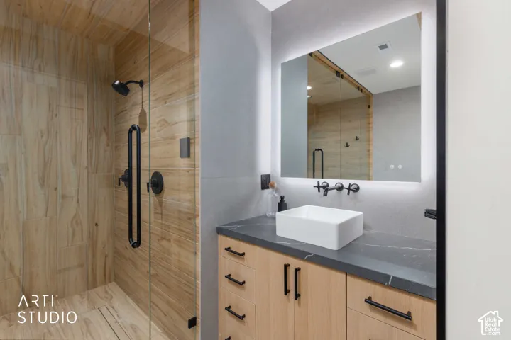 Glass-enclosed shower with wood-finish wall and floor tiling