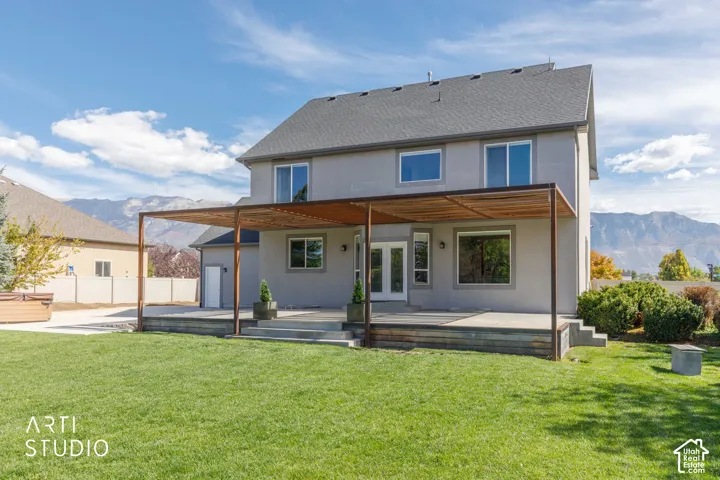 Expansive backyard featuring a manicured lawn, a large patio, and a wood-slat pergola
