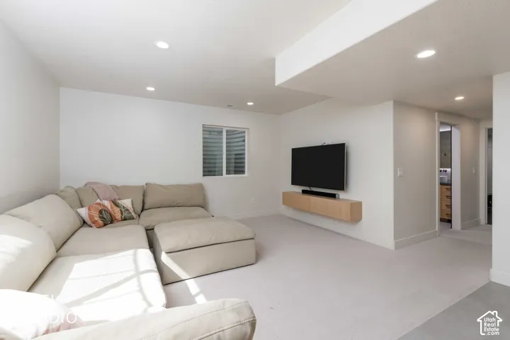 Recessed lighting throughout, carpet flooring, and a wall-mounted media console