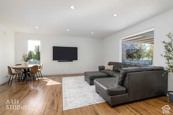Wood-finish flooring throughout, recessed ceiling lighting, ample natural light from multiple windows, and a dedicated wall-mounted display area