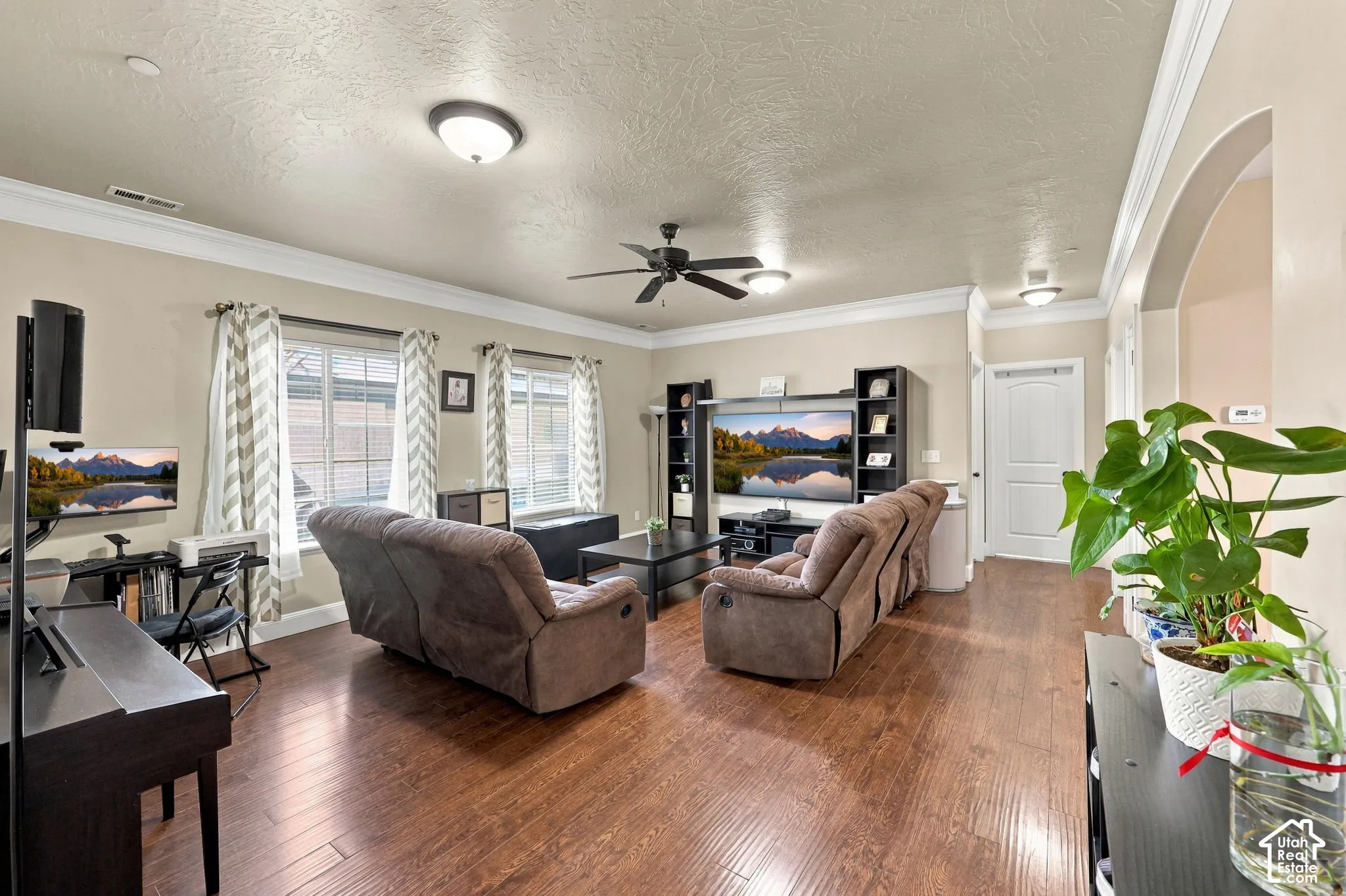 Hardwood-finish flooring, crown molding, arched entry, recessed lighting, and a ceiling fan